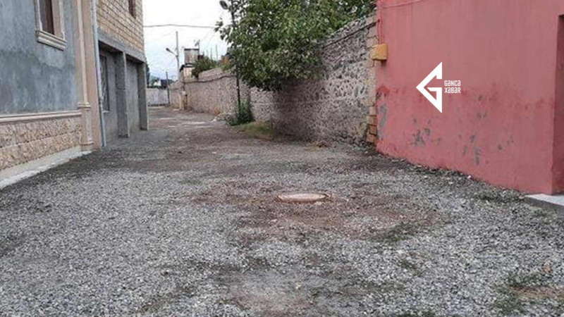 Gəncədə küçələrdən birində yağmurlu havada yağış suları evlərin həyətlərinə dolur