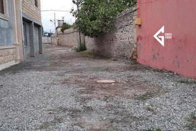 Gəncədə küçələrdən birində yağmurlu havada yağış suları evlərin həyətlərinə dolur